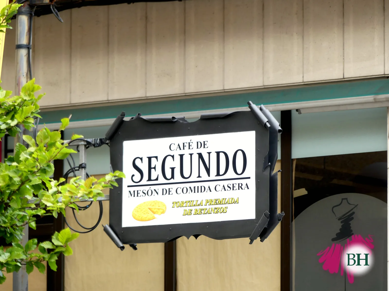 Letreiro colgado na fachada do Mesón Café de Segundo: «Café de Segundo. Mesón de comida casera», co debuxo dunha tortilla e a lenda «Tortilla premiada de Betanzos».