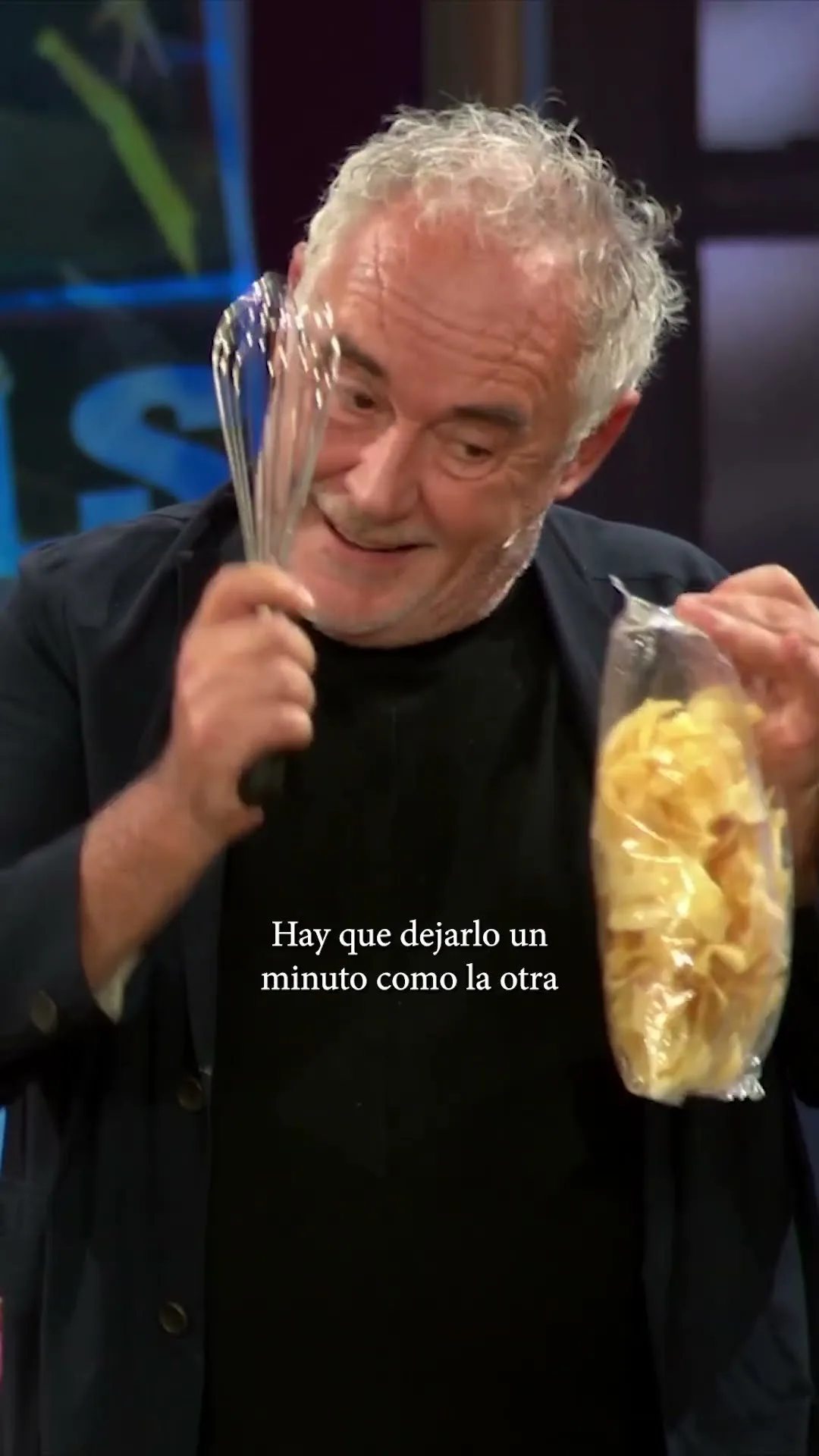 Ferran Adrià, cunha variña nunha man e unha bolsa de patacas fritas na outra, no plató de La Revuelta.