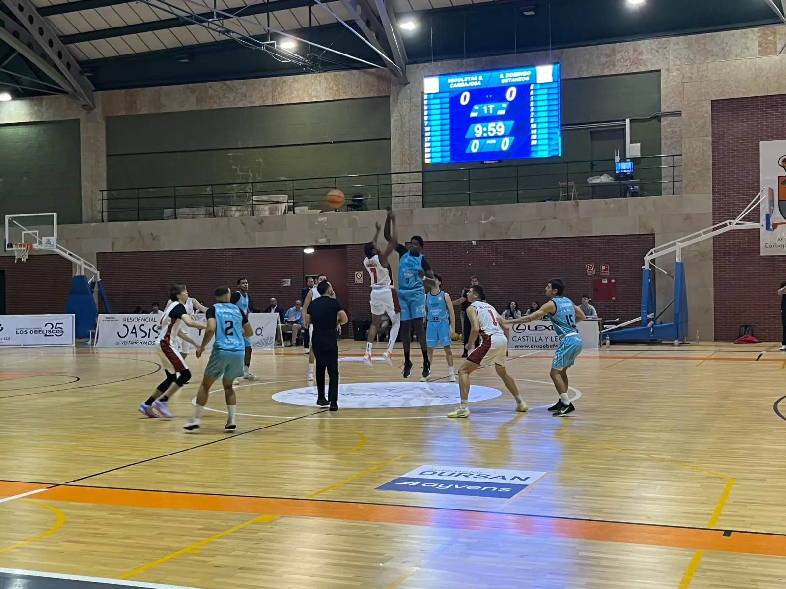 Salto inicial del partido entre el Recoletas Salud, de azul celeste, y el Ineltrón Santo Domingo, de blanco y rojo, en el pabellón de Carbajosa de La Sagrada con el marcador a cero.